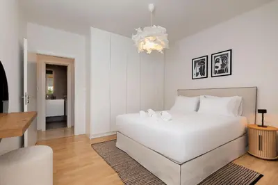 a white bedroom with a white bed and a chandelier at Elegant & Central 3BR in Glyfada in Athens