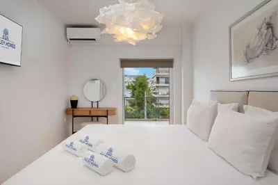a bedroom with a white bed with white pillows and a chandelier at Elegant & Central 3BR in Glyfada in Athens
