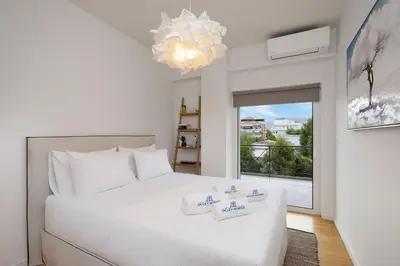 a bedroom with a white bed and a large window at Elegant & Central 3BR in Glyfada in Athens