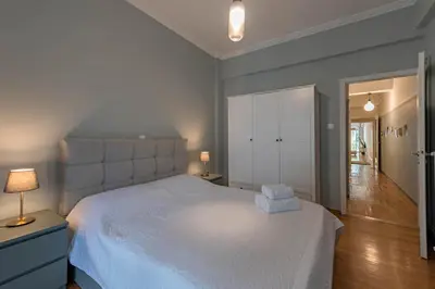 a bedroom with a large white bed and a hallway at Empyrean Apartment in Athens