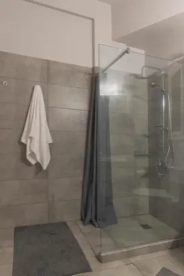 a bathroom with a shower with a glass door at Empyrean Apartment in Athens