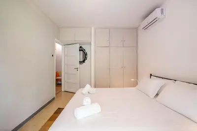 a white bedroom with a bed with two towels on it at Very comfortable, close to Acropolis in Athens