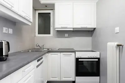 a kitchen with white cabinets and a sink and a stove at Graceful 2BR Apartment in Paleo Faliro by UPSTREET in Athens