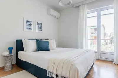 a white bedroom with a large bed and a window at Graceful 2BR Apartment in Paleo Faliro by UPSTREET in Athens