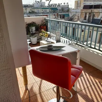 a red chair sitting on a balcony with a table at v&k apartment in Athens