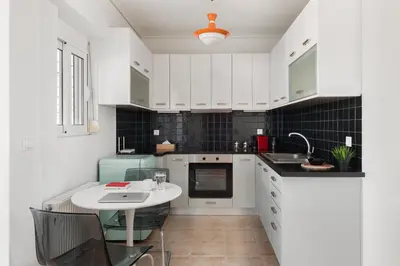 a white kitchen with a sink and a table at Large terrace studio in Athens