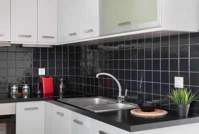 a kitchen with a sink and a black tiled wall at Large terrace studio in Athens