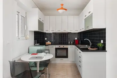 a white kitchen with a sink and a table at Large terrace studio in Athens