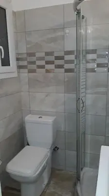 a bathroom with a toilet and a glass shower at Cozy and spacious 2 BDR Apt 15 min from the city center in Athens