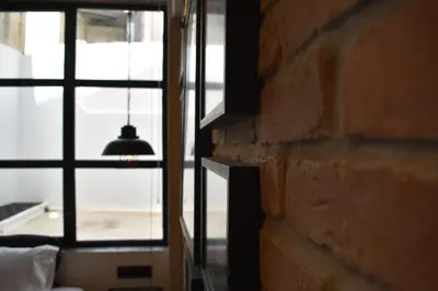 a room with a brick wall and a hanging lamp at City Plus by CityBee in Athens