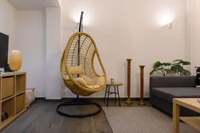 a rattan chair in a living room with a couch at Kastella Bohemian Pied a Terre in Piraeus