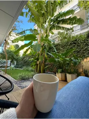a person holding a cup of coffee on a table at Viktoria's garden home in Athens