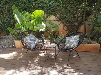 three chairs sitting on a wooden deck with plants at Viktoria's garden home in Athens