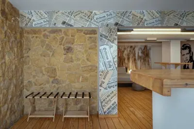 a room with a stone wall with a table and benches at Plastiko Loft in Athens
