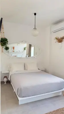 a white bedroom with a white bed and a mirror at Stylish Studio in Psyri in Athens