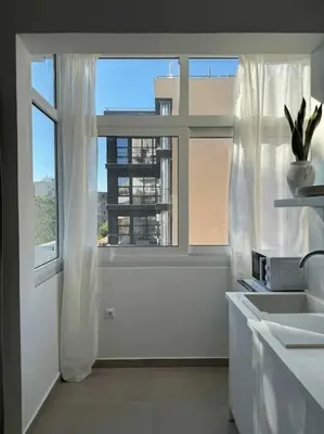 a white bathroom with a window and a sink at Stylish Studio in Psyri in Athens