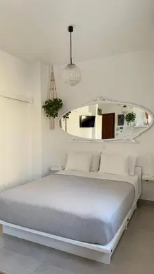a white bedroom with a bed and a mirror at Stylish Studio in Psyri in Athens