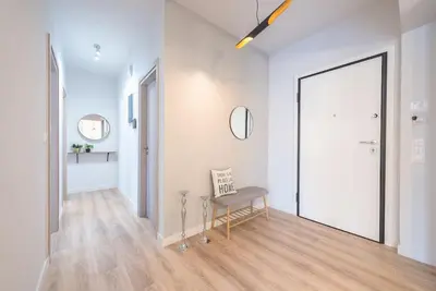a white hallway with a chair and a mirror at Urban Αpartment in Athens