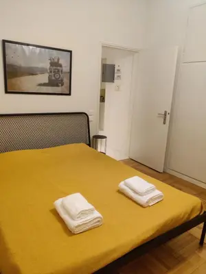a bedroom with a yellow bed with two towels on it at Pagkrati Apartment 80 in Athens
