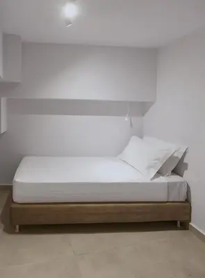 a bed in a room with a white wall at En Plaka - Athens Elegant Estate in Athens