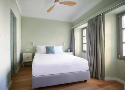 a bedroom with a white bed with a ceiling fan at En Plaka - Athens Elegant Estate in Athens