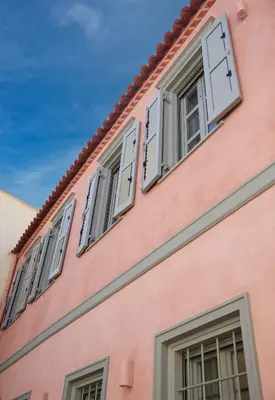 a pink building with white shuttered windows at En Plaka - Athens Elegant Estate in Athens