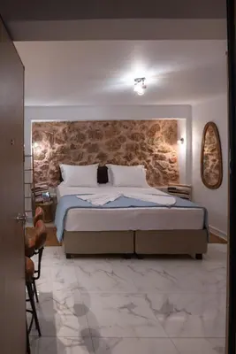 a bedroom with a large bed with a stone wall at just for two in Athens in Athens
