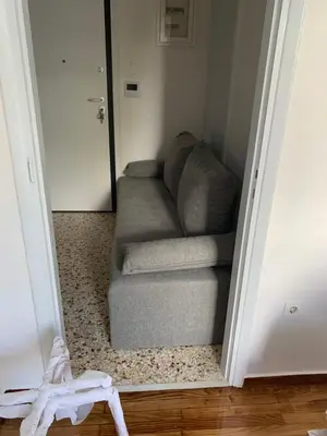 a gray couch sitting in a hallway next to a door at ALEX house in Athens