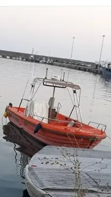 a red boat is sitting in the water at ALEX house in Athens