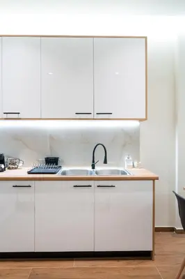 a kitchen with white cabinets and a sink at Vitsas House By Greece Apartments in Athens