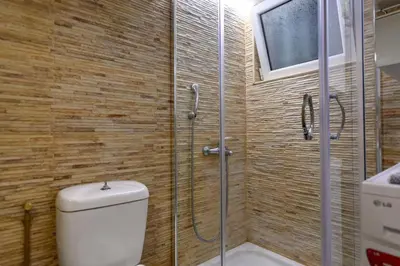 a bathroom with a toilet and a glass shower at Voguish Design 2 bedroom Den in Athens