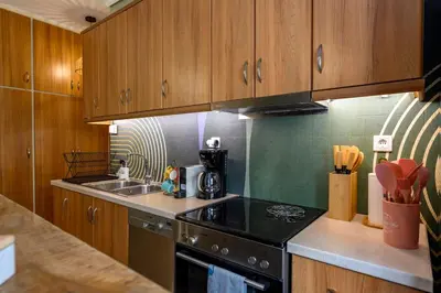 a kitchen with wooden cabinets and a stove top oven at Voguish Design 2 bedroom Den in Athens