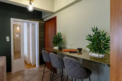 a kitchen with a counter with chairs and plants at Voguish Design 2 bedroom Den in Athens