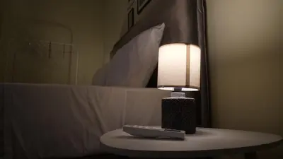 a lamp sitting on a table next to a bed at Classic Athenian house 2mins from metro in Athens