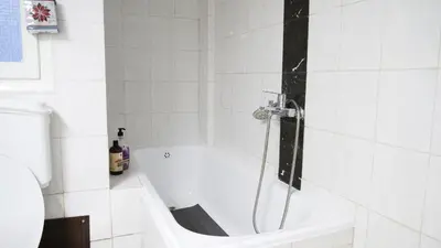a white bath tub in a white tiled bathroom at Classic Athenian house 2mins from metro in Athens