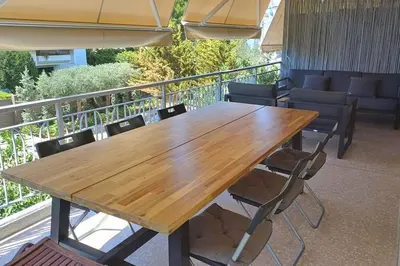 a wooden table and chairs on a balcony at quiet apartment near the sea in Athens
