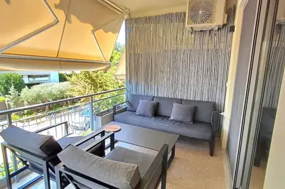 a balcony with a couch and chairs and an umbrella at quiet apartment near the sea in Athens