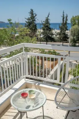 a balcony with two chairs and a table with bowls on it at Athens Riviera 2BR Luxury Apartment in Athens