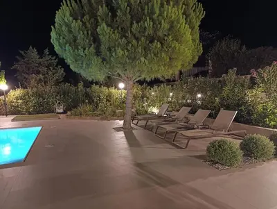 a row of lounge chairs under a tree at night at Country house for4 in Markopoulo