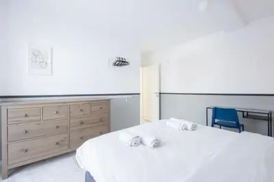 a bedroom with a white bed and a blue chair at Elegant Coastal Haven Fully Renovated 3-Bedroom Apartment in Athens