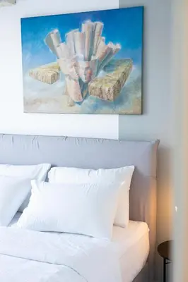 a bedroom with a white bed with a painting above it at Elegant Coastal Haven Fully Renovated 3-Bedroom Apartment in Athens