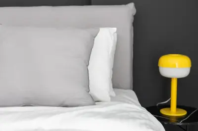 a bed with a yellow lamp next to a white pillow at Elegant Coastal Haven Fully Renovated 3-Bedroom Apartment in Athens