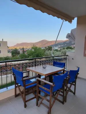 a wooden table and chairs on a balcony with a view at Gabi's Apartment in Porto Rafti
