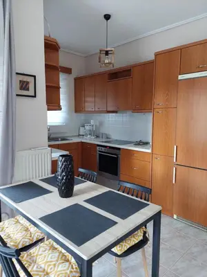 a kitchen with wooden cabinets and a table with chairs at Gabi's Apartment in Porto Rafti