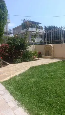 a yard with green grass next to a building at Gabi's Apartment in Porto Rafti