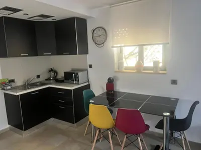 a kitchen with a table and chairs and a clock on the wall at Апартаменты в Вари in Vari