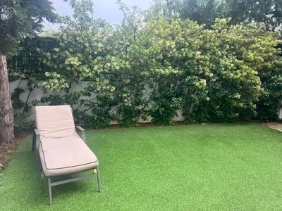 a chair sitting on the grass in front of a bush at Апартаменты в Вари in Vari