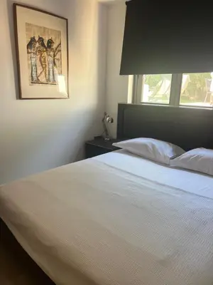 a bedroom with a white bed with a picture on the wall at Апартаменты в Вари in Vari