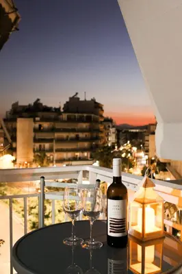 a bottle of wine and two glasses on a table on a balcony at 50 Steps Apart Metro Neos Kosmos in Athens