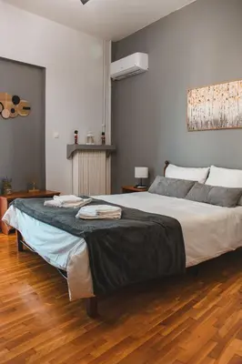 a large bed in a bedroom with a wooden floor at 50 Steps Apart Metro Neos Kosmos in Athens